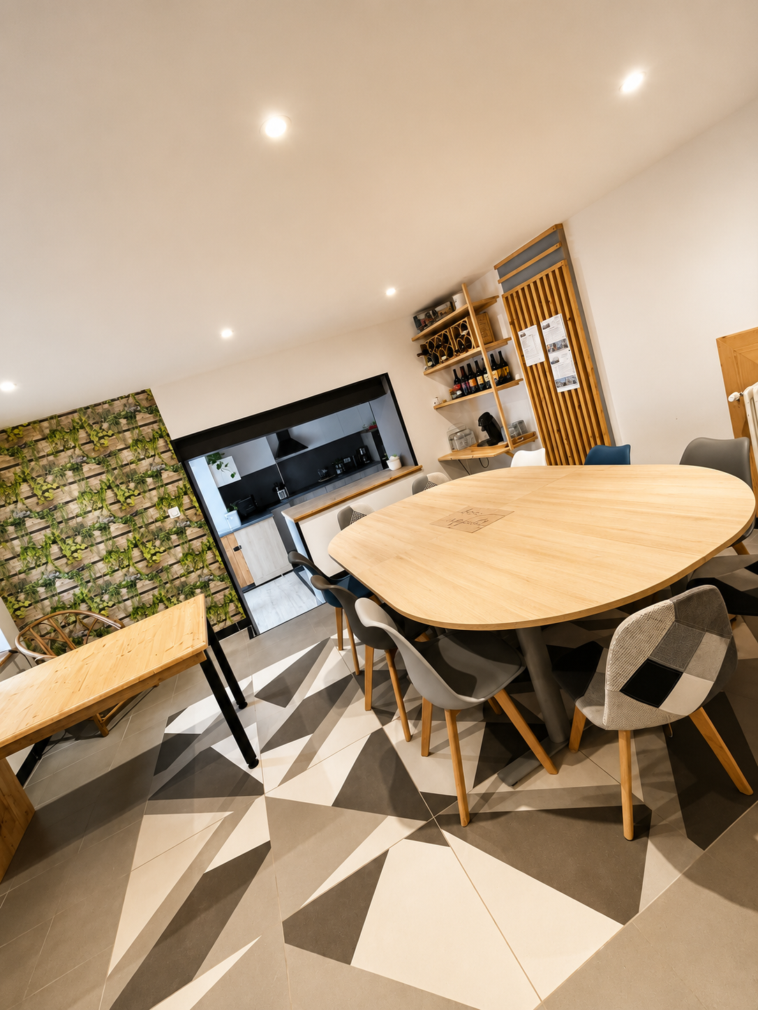 Salle à manger du gîte avec grande table en bois, mur végétal et cuisine ouverte — Ferme rénovée Pilat
